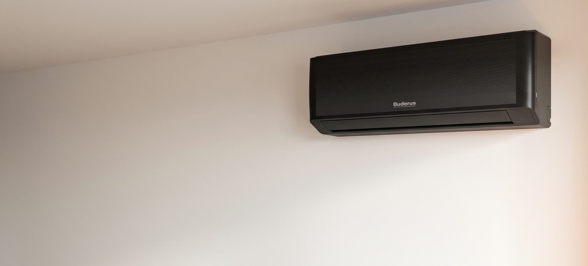 Schmales Split-Klimagerät an der Wand eines hellen Wohnzimmers über einem Sofa